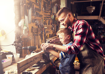 Image showing father and son with plane shaving wood at workshop