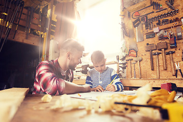 Image showing happy father and son with blueprint at workshop