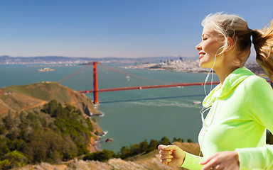 Image showing woman with earphones running over san francisco