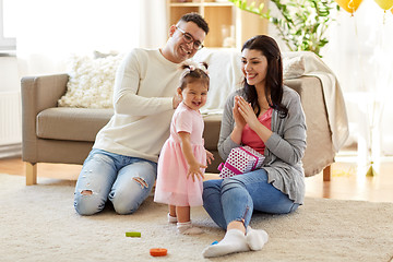 Image showing baby girl with birthday gift and parents at home