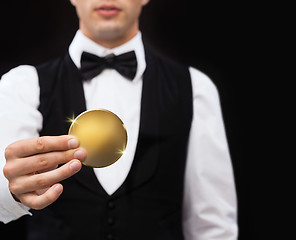 Image showing close up of casino dealer holding golden coin