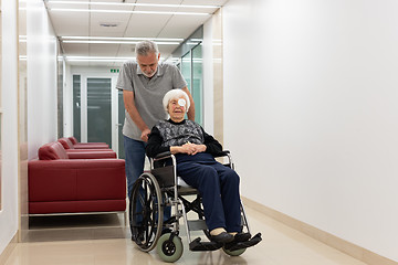 Image showing Middle aged man helping and taking to elderly 95 years old woman sitting in the wheelchair.