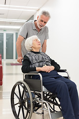 Image showing Middle aged man helping and taking to elderly 95 years old woman sitting in the wheelchair.