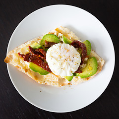 Image showing Poached egg on a toasted bun with avocados and dried tomatoes.
