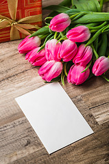 Image showing Beautiful bouquet from pink tulips and a gift on a table