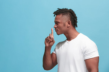 Image showing The young afro-american man whispering a secret behind her hand over blue background