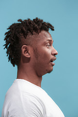 Image showing The surprised business Afro-American man standing and looking blue background. Profile view.