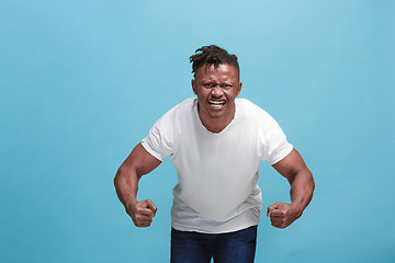Image showing The young emotional angry afro man screaming on blue studio background