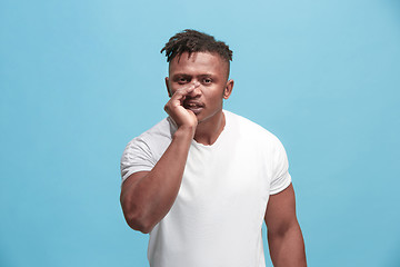 Image showing The young afro-american man whispering a secret behind her hand over blue background