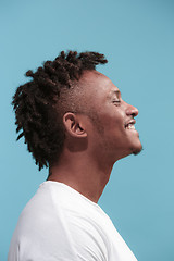 Image showing The happy business Afro-American man standing and smiling against blue background. Profile view.