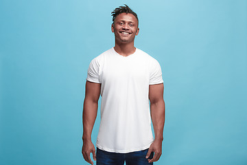 Image showing The happy afro-american business man standing and smiling against blue background.