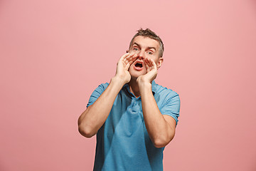 Image showing Isolated on pink young casual man shouting at studio