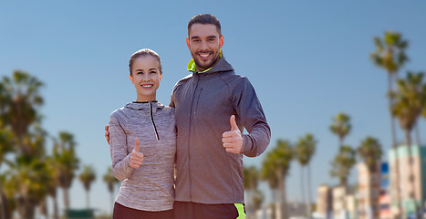 Image showing smiling couple in sport clothes showing thumbs up