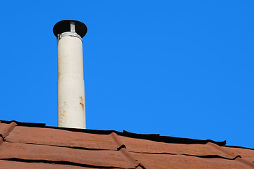 Image showing Old chimney of asbestos pipe over a rusty metal roof 