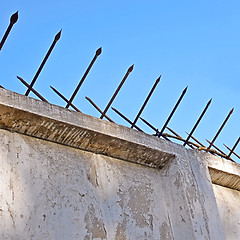 Image showing Old concrete fence with two-sided acute iron pins