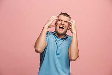 Image showing The young emotional angry man screaming on pink studio background