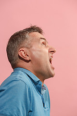 Image showing The young emotional angry man screaming on pink studio background