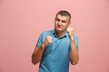 Image showing The young emotional angry man screaming on pink studio background