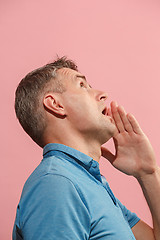 Image showing The young man whispering a secret behind her hand over pink background