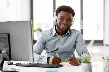 Image showing businessman with headphones and papers at office