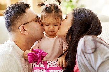 Image showing parents kissing little daughter with birthday gift