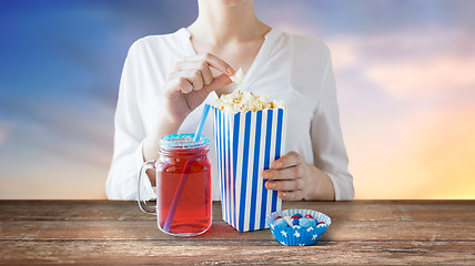 Image showing woman eating popcorn with drink in glass mason jar