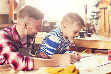 Image showing happy father and son with blueprint at workshop