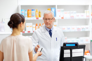 Image showing apothecary taking customer credit card at pharmacy