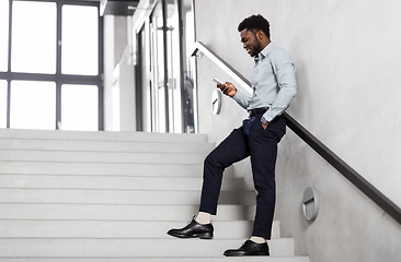 Image showing businessman with smartphone at office stairs