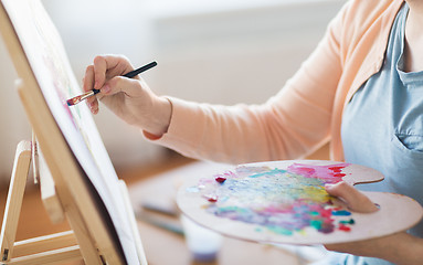 Image showing artist with palette and brush painting at studio