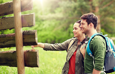 Image showing smiling couple at signpost with backpacks hiking