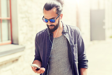 Image showing man with earphones and smartphone walking in city