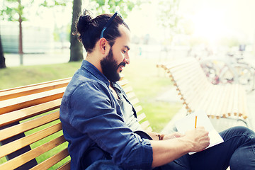 Image showing man with notebook or diary writing on city street