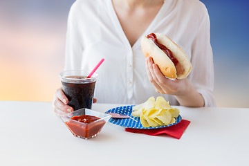 Image showing close up of woman eating hot dog with cola