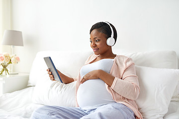 Image showing pregnant woman in headphones with tablet pc