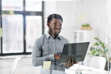 Image showing businessman with laptop at office glass board