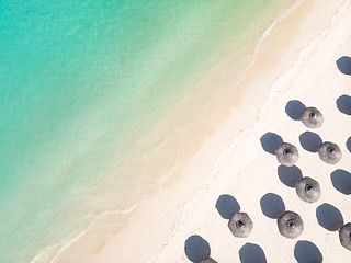 Image showing Aerial view of amazing tropical white sandy beach with palm leaves umbrellas and turquoise sea.