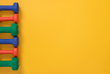 Image showing Colorful dumbbells on yellow background