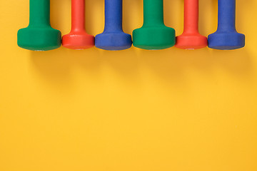 Image showing Colorful dumbbells on joyful yellow background