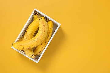 Image showing Box of ripe bananas on vivid yellow background