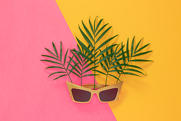 Image showing Palm leaves and sunglasses on pink and yellow background