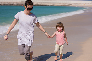 Image showing mother and daughter running on the beach