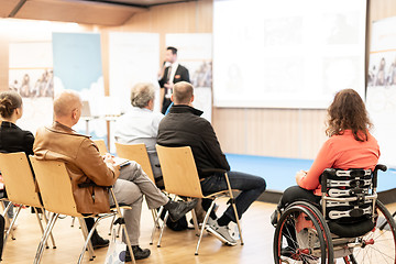 Image showing Rear view of nrecognizable woman on a wheelchair participating at business conference talk.