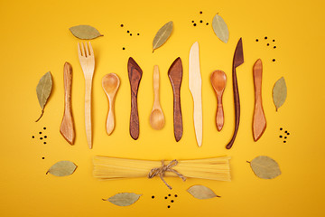 Image showing Wooden utensils, pasta and spices on yellow background