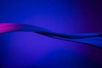 Image showing Smooth elegant transparent blue cloth separated on blue background.