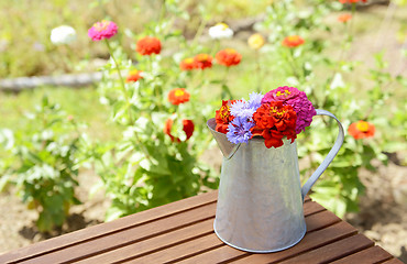 Image showing Metal pitcher full of brightly coloured flowers