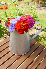 Image showing Pitcher filled with fresh flowers on a garden table