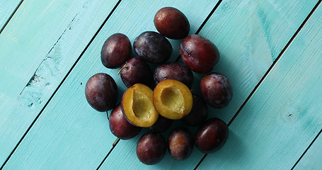 Image showing Pile of ripe plums on blue wood