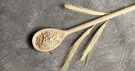 Image showing Wooden spoon with oats on table