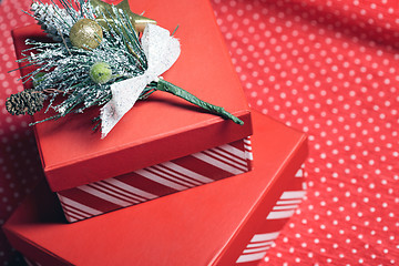 Image showing Christmas gift boxes and twig of Christmas tree on a red wrappin